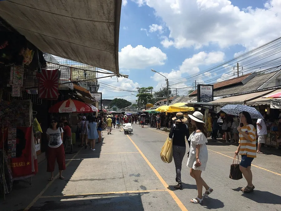 Calle del mercado de Chatuchak en Bangkok: puestos con toldos, sombrillas y compradores paseando entre los pasillos