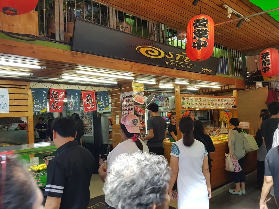 Clientes ante una tienda de sushi del mercado Wang Lang