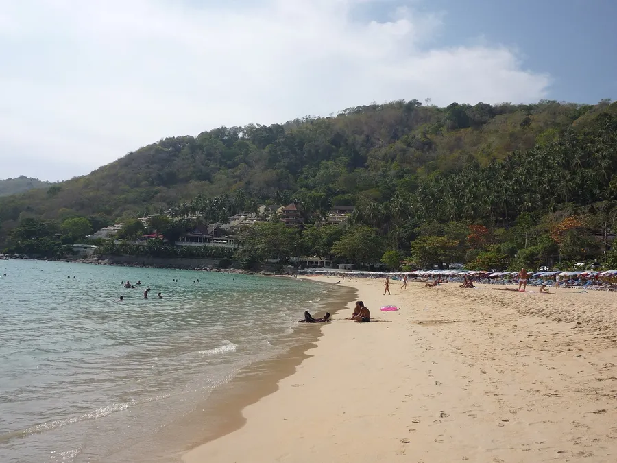 Arena y agua azul de Nai Harn Beach en el sur de Phuket