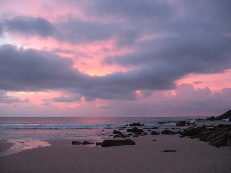 Orilla rocosa y cielo rosado en Nai Thon Beach