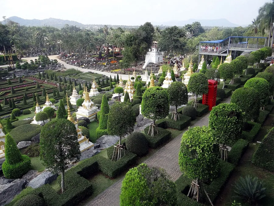 Vista elevada del jardín francés de Nong Nooch, con setos recortados, topiaria y réplicas de chedis dorados