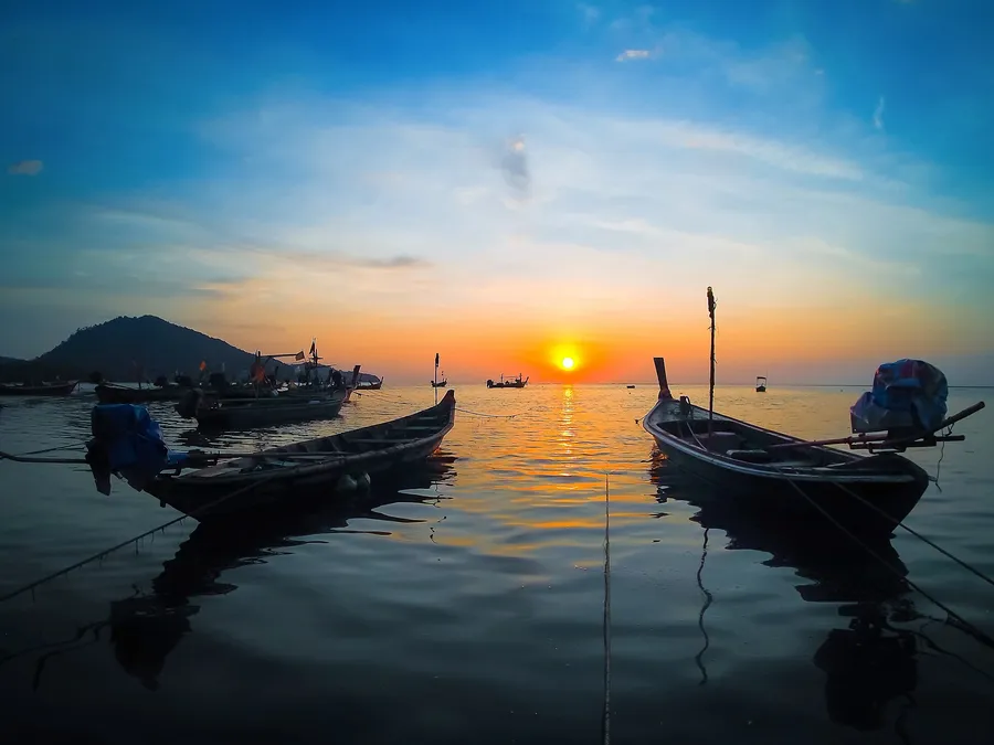 Barcas de cola larga fondeadas frente a Sirinat al atardecer, en el norte de Phuket
