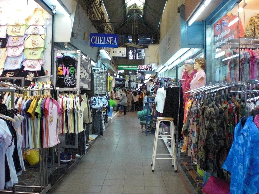 Pasillo del mercado de Pratunam en Bangkok, con percheros de ropa y tiendas mayoristas a ambos lados