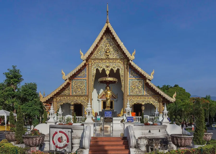 Viharn luang de Wat Phra Singh en Chiang Mai: fachada dorada, tejado escalonado Lanna y Buda de pie en la entrada