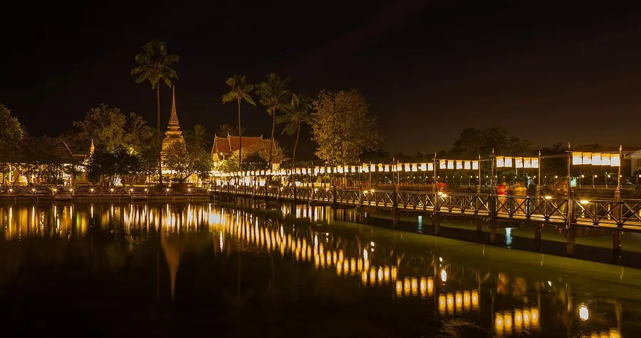 Templo y estanque de Wat Traphang Thong iluminados durante una celebración